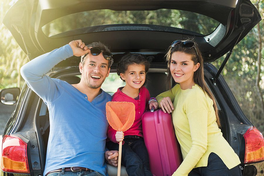 Personal Insurance - A Father, Mother and Their Son are Standing and Leaning in the Back of Their Car Getting Ready for a Trip on a Sunny Day